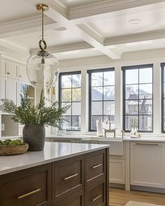 a kitchen with white cabinets and large windows