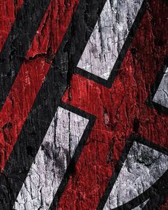 a red and black abstract painting on the side of a rock wall with white lines