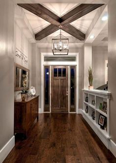 an entry way with wooden floors and white walls, wood beams on the ceiling, and a chandelier hanging from the ceiling