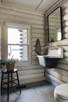 a white toilet sitting next to a sink in a bathroom under a window with a potted plant