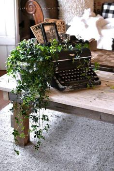 an old fashioned typewriter sitting on top of a table next to a potted plant