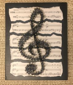 an art piece made out of sheet music with string and beads hanging from the strings