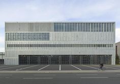 an empty parking lot in front of a building with two people riding bikes on it