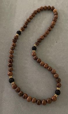 a wooden beaded necklace with black and brown beads on a gray surface, resting on a table