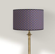 a lamp with a blue and pink shade on it's side next to a white wall