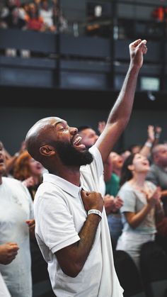 a man with his arms up in the air while standing next to other people clapping