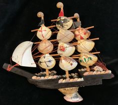 a small model ship with lots of sails and rocks on it's bottom deck