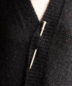 a close up of a person wearing a black cardigan with two pins on it