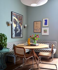 a living room with a striped couch, table and pictures on the wall above it