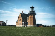 a large brick building with a light house on top in the middle of a grassy field