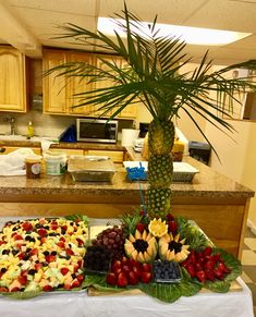 two trays filled with fruit on top of a table next to a palm tree