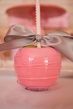 a pink ball with a bow on it sitting on top of a table next to a candle