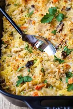 a casserole dish with carrots, mushrooms and parsley on top is being served with a spoon