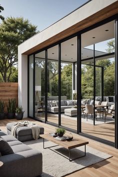 a living room filled with furniture and lots of glass doors on the side of a building