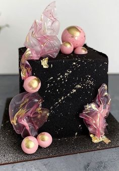 a black cake with pink and gold decorations