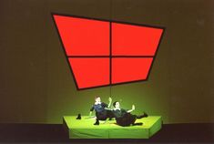 two people laying on the ground in front of a red and black square shaped object