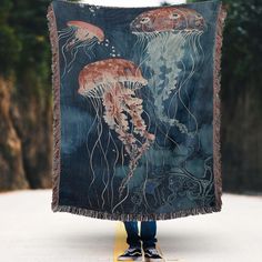 a person holding up a tapestry with jellyfishs on it