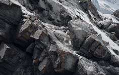 some rocks and snow on the side of a mountain