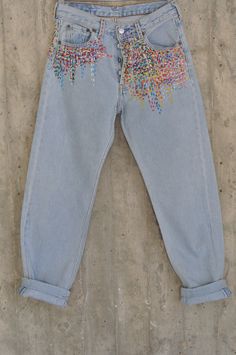 a pair of light blue jeans with colorful sequins on them