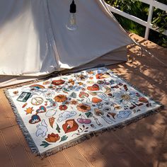 a white tent sitting on top of a wooden floor next to a rug covered in stickers