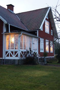 a red house with white trim and windows on the front porch is lit up at night