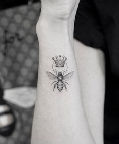 a bee with a crown on its head tattooing it's back arm and wrist