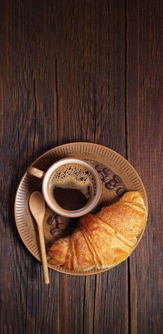 a croissant and coffee on a wooden table