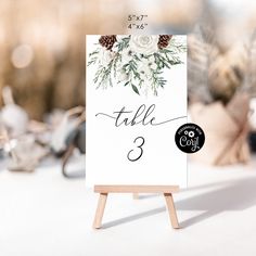 an easel with a table number on it and flowers in the center is shown