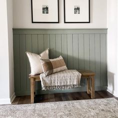 two framed pictures hang on the wall above a bench in a room with wood flooring