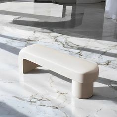 a white bench sitting on top of a marble floor