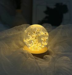 a snow globe sitting on top of a bed covered in white sheets and light bulbs