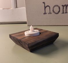 a small white object sitting on top of a wooden table next to a sign that says home