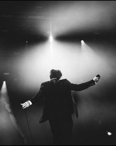 a man in a suit standing on stage with his arms outstretched