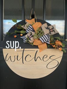 a wooden sign that says sup, witches on it with flowers and leaves hanging from the front