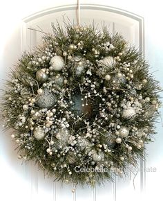 a wreath is hanging on the front door with balls and greenery around it's edges