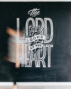 a person walking past a blackboard with the words lord and heart on it