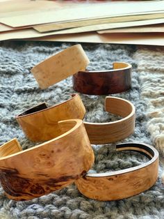 four wooden bracelets sitting on top of a rug next to a pile of books