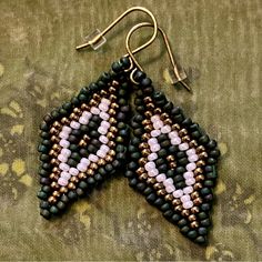 two pairs of beaded earrings sitting on top of a green cloth covered tablecloth