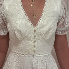 a woman wearing a white dress with a cross on the front and a name tag attached to her chest