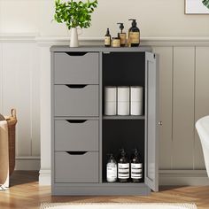 a bathroom cabinet with three drawers and some toiletries on it's shelf next to a potted plant