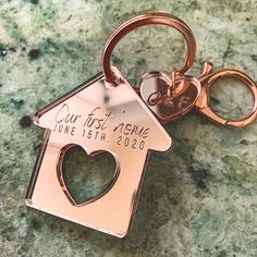 a house shaped keychain with the words our first home engraved on it's side