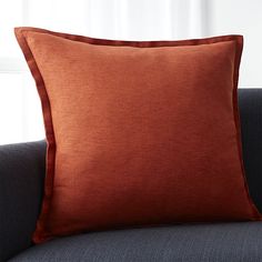 an orange pillow sitting on top of a blue couch