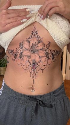 a woman's stomach with a flower tattoo on her belly and the bottom part of her stomach