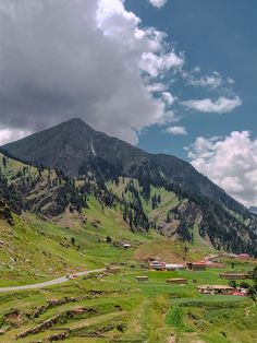 the mountains are covered in green grass and trees, while houses sit on top of them