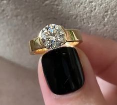 a woman's hand holding a black and gold ring with a diamond on it