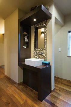 a bathroom with a sink and mirror in it's center wall, along with wooden flooring