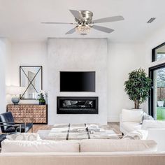 a living room with white couches and a flat screen tv mounted on the wall