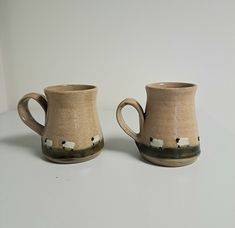 two mugs with sheep painted on them sitting next to each other in front of a white wall