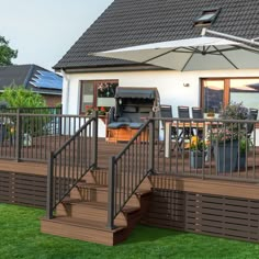 a deck with an umbrella over it next to a patio and dining table on the grass