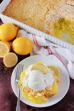 a white plate topped with ice cream next to lemons and a baking pan filled with cake